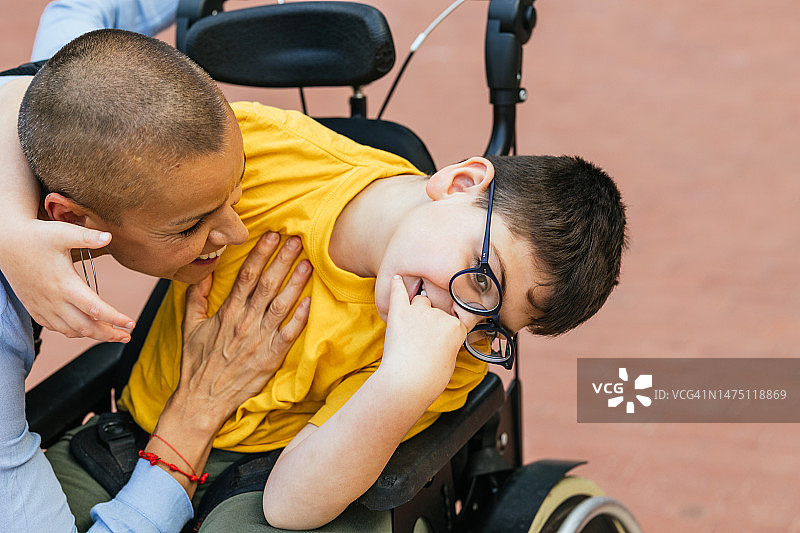 阳光明媚的日子里，四肢瘫痪的男孩和母亲共度美好时光图片素材