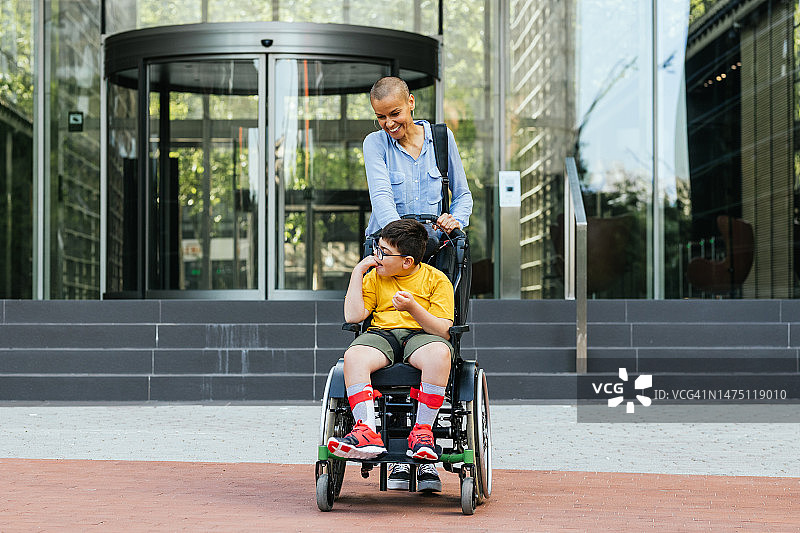 患有四肢瘫痪的儿童与母亲在城市里共度时光的正面图图片素材