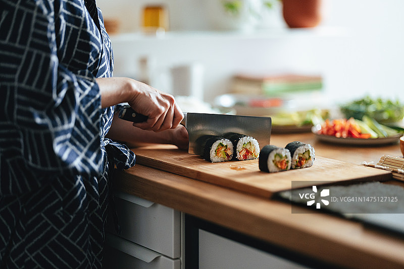 女人切割寿司卷的手部特写图片素材