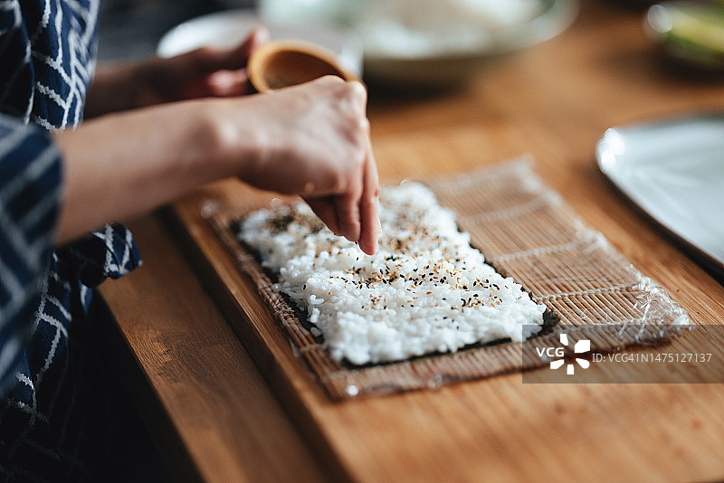 女人在紫菜上放芝麻的近距离照片图片素材