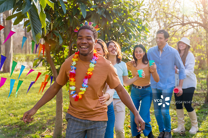 一群不同种族的朋友在公园里庆祝生日，跳舞和一起跳康茄舞图片素材
