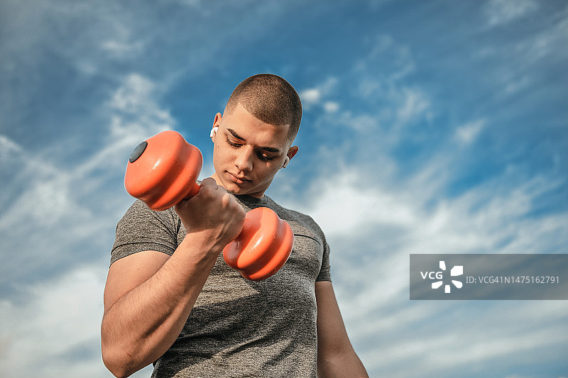 在公园里举重锻炼的年轻男子图片素材