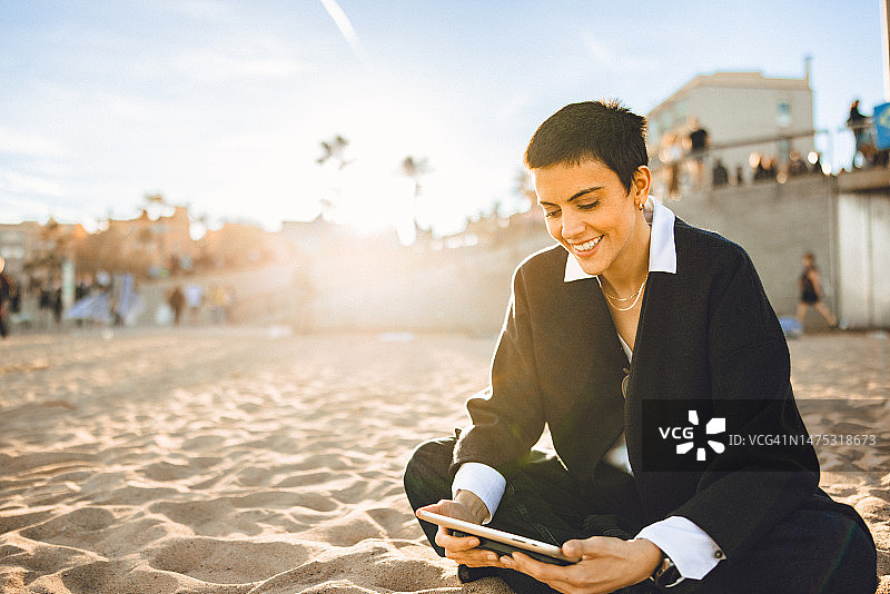 在城市海滩用平板电脑观看视频的年轻女人图片素材