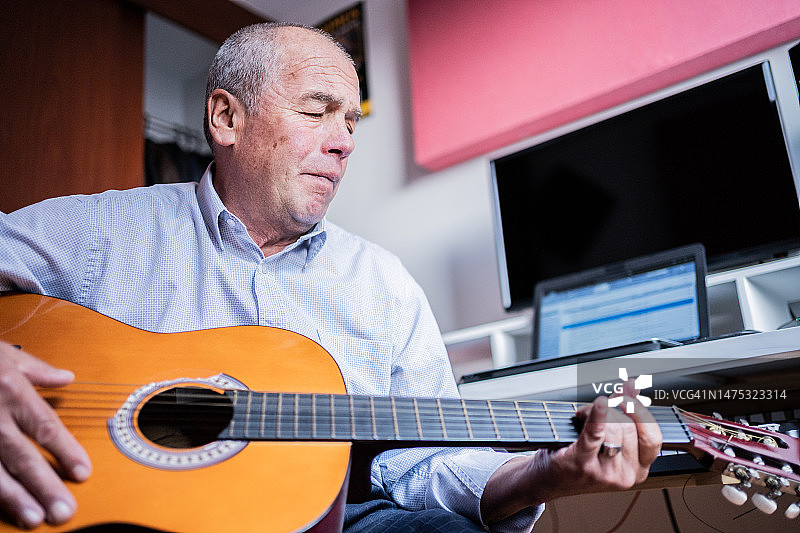 年长的男人在家弹奏原声吉他图片素材