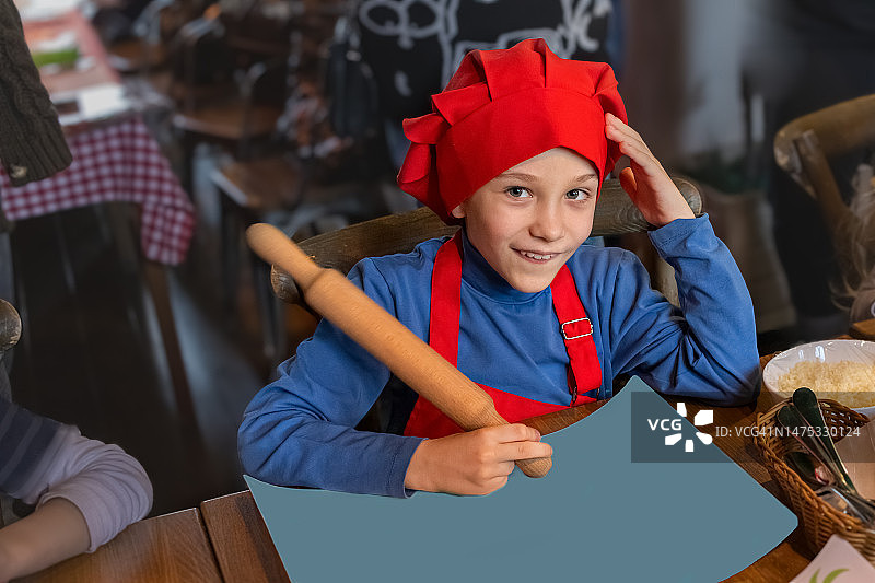 拿着木制擀面杖的微笑厨师男孩图片素材