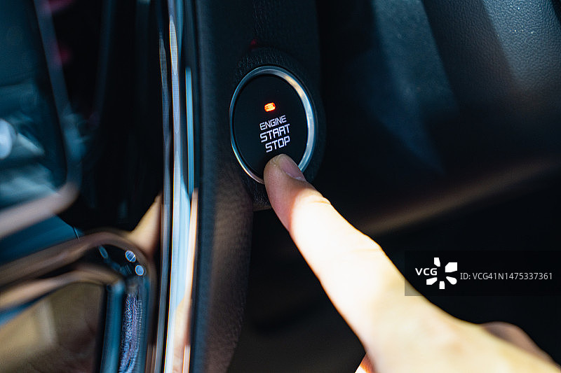 手伸向汽车发动机启动按钮的特写图片素材