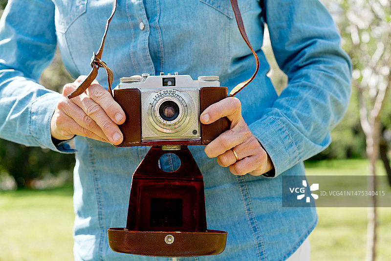 拿着老式照相机的中年妇女的手图片素材