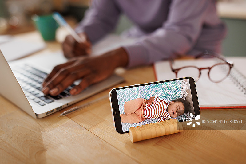 母亲使用笔记本电脑时婴儿监视器手机应用特写镜头图片素材