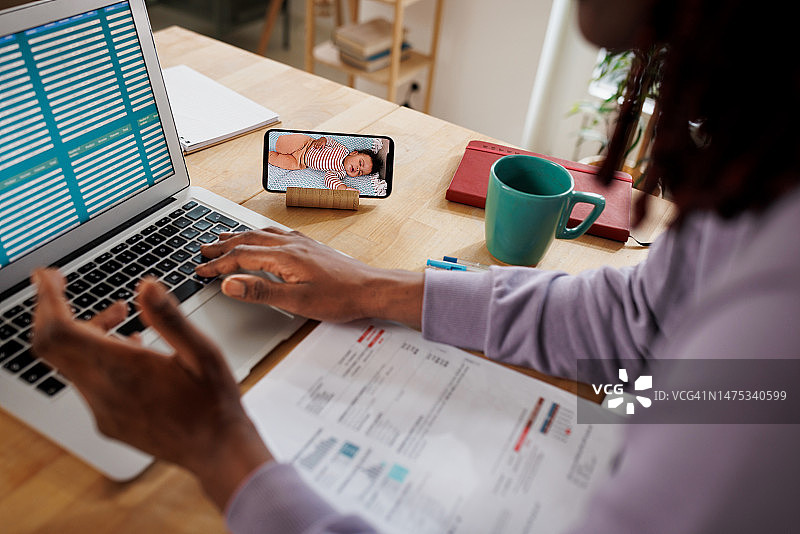 母亲在家工作时使用婴儿监视器查看儿子的情况图片素材