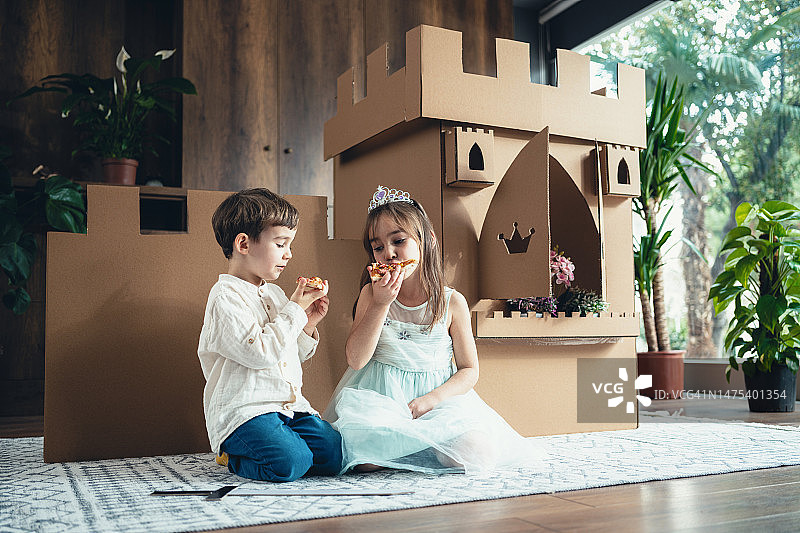 可爱的小公主和小王子在家玩纸板城堡角色扮演游戏图片素材