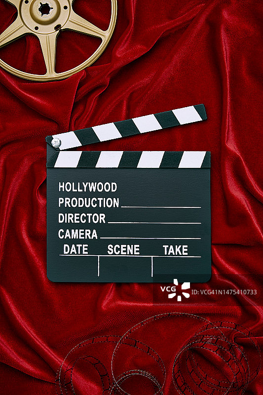 红色缎纹背景上的电影场记板、胶片和电影，有复制空间图片素材