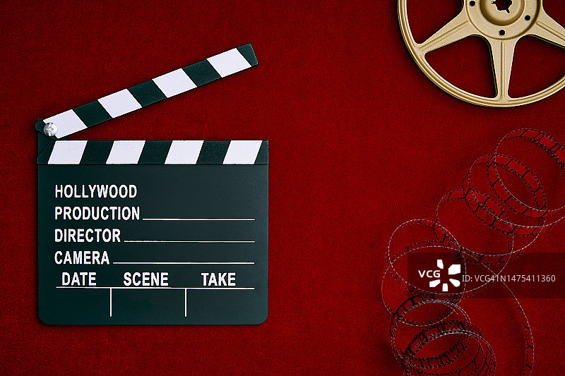 红色缎纹背景上的电影场记板、胶片和电影，有复制空间图片素材
