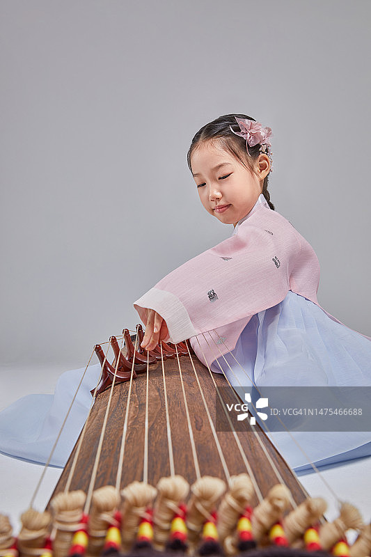 女孩演奏伽倻琴，身穿韩服，面带微笑图片素材