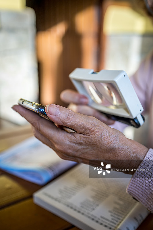 年长的女人用放大镜阅读智能手机图片素材