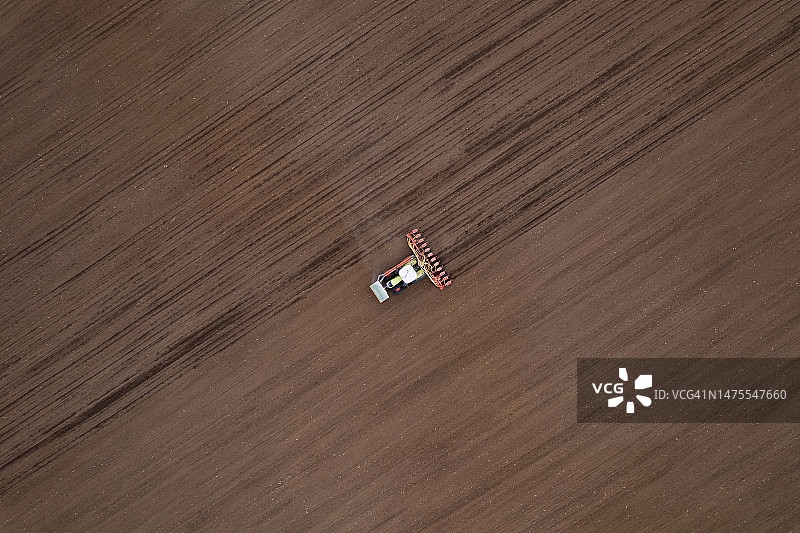 农民驾驶拖拉机在春季耕地上播种无人机航拍视角图片素材
