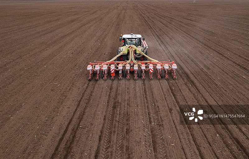 农民驾驶拖拉机在春季耕地上播种无人机航拍视角图片素材