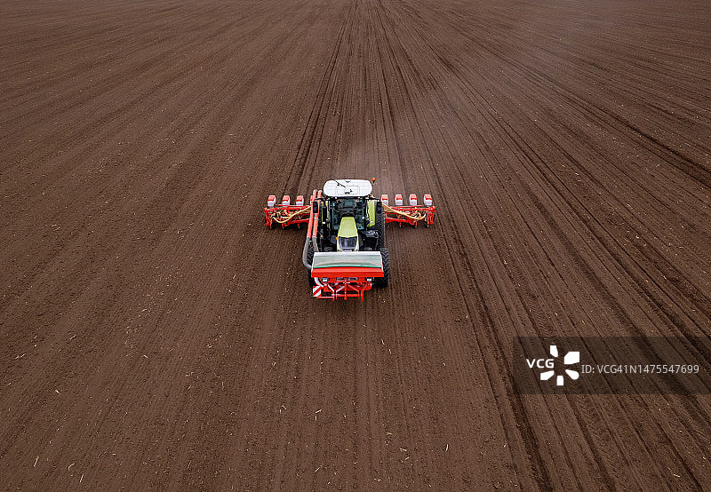农民驾驶拖拉机在春季耕地上播种无人机航拍视角图片素材