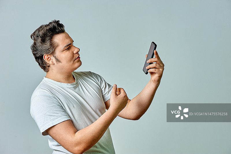 男人在灰色背景下看手机屏幕图片素材