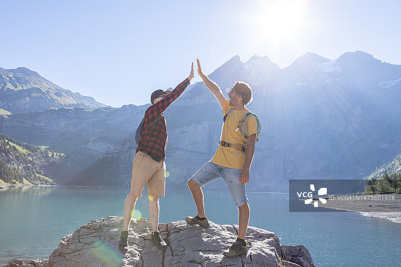 两个徒步旅行者在岩石顶上庆祝成功并击掌图片素材