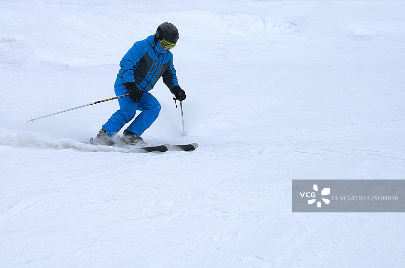 一名身穿蓝色运动服的男子在雪坡上滑雪，俄罗斯彼尔姆边疆区彼尔姆图片素材