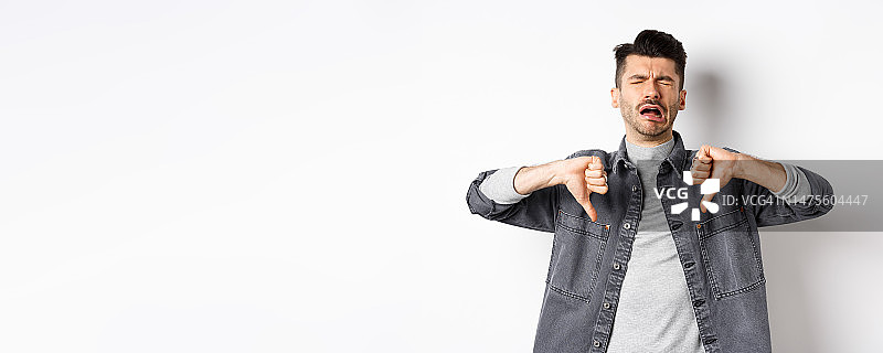 悲伤的男人哭泣并竖起拇指向下，抱怨图片素材