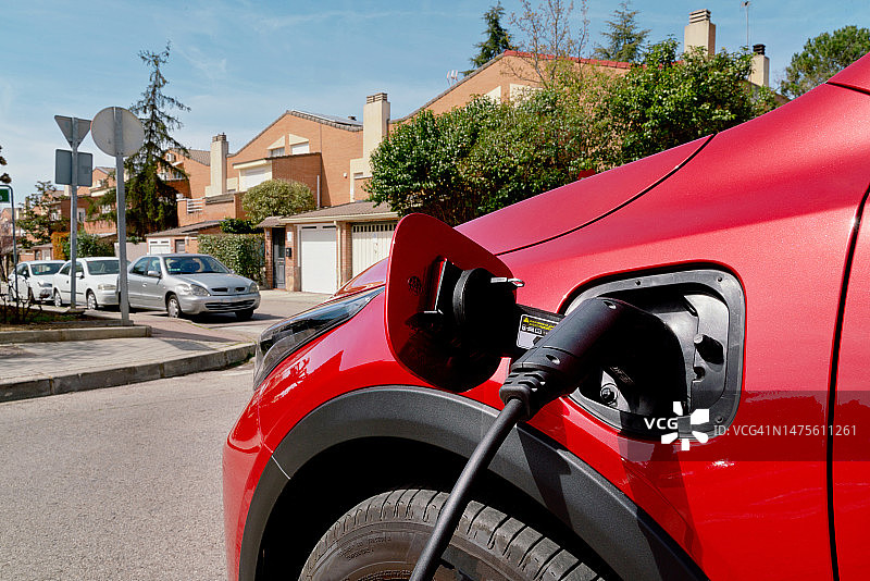红色混合动力汽车在充电站充电的细节图片素材