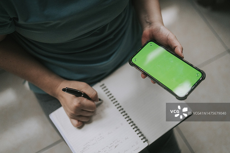 中国女人在色度键中写笔记，参考智能手机特写图片素材