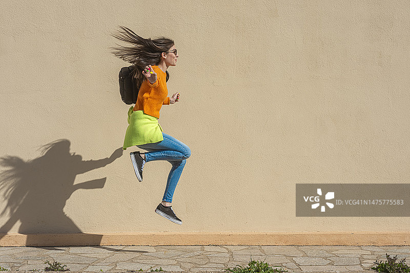 背着背包跳跃奔向学校的女人图片素材