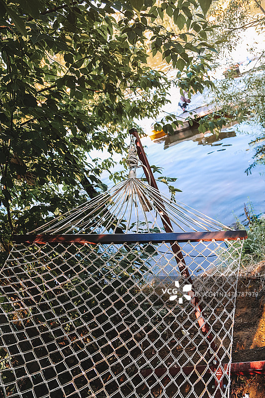 阳光明媚的夏日早晨，模糊的湖岸背景下的空吊床图片素材