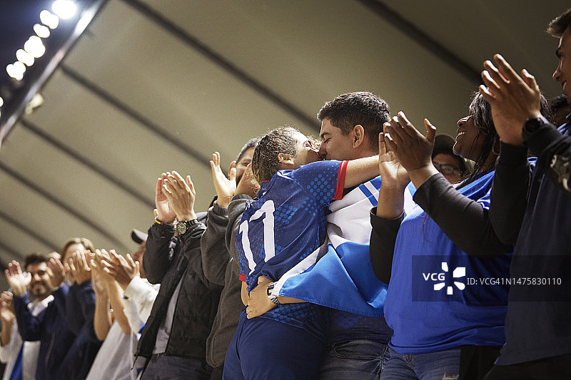 一位女运动员倾身亲吻她的伴侣，她的伴侣搂着她的腰图片素材