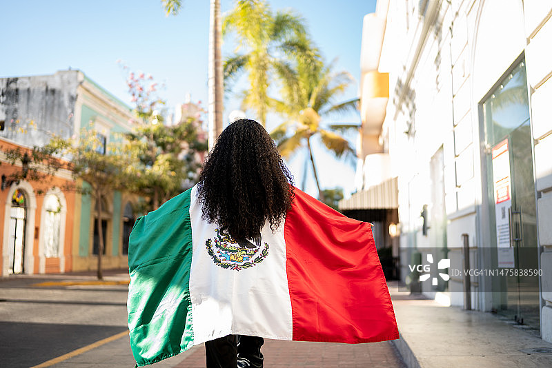 女人在街上手持墨西哥国旗行走图片素材