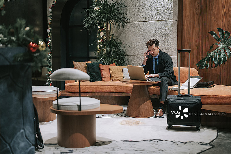 亚洲商人坐在沙发上在机场休息室打电话图片素材