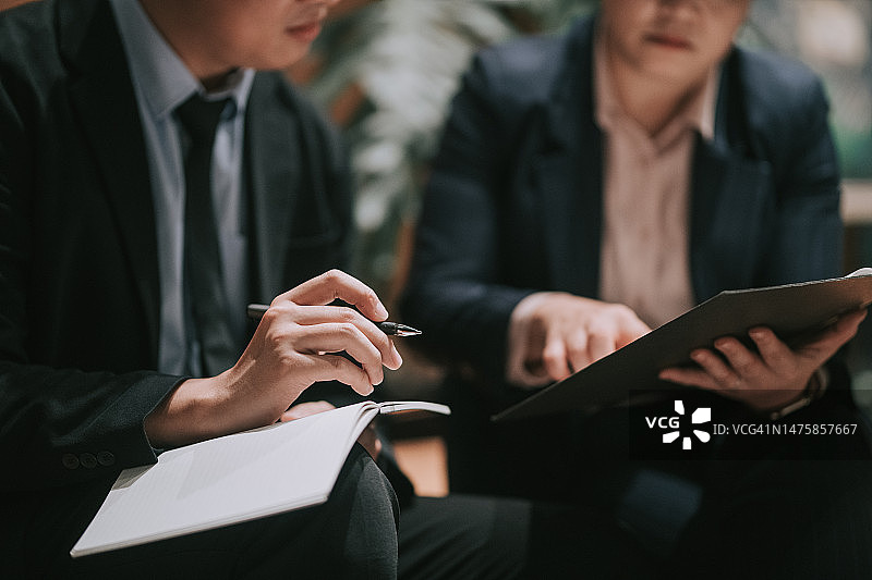 亚洲男人近距离做笔记，听同事讲话图片素材