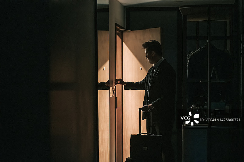 亚裔商人刷卡进入酒店房间的轮廓剪影图片素材