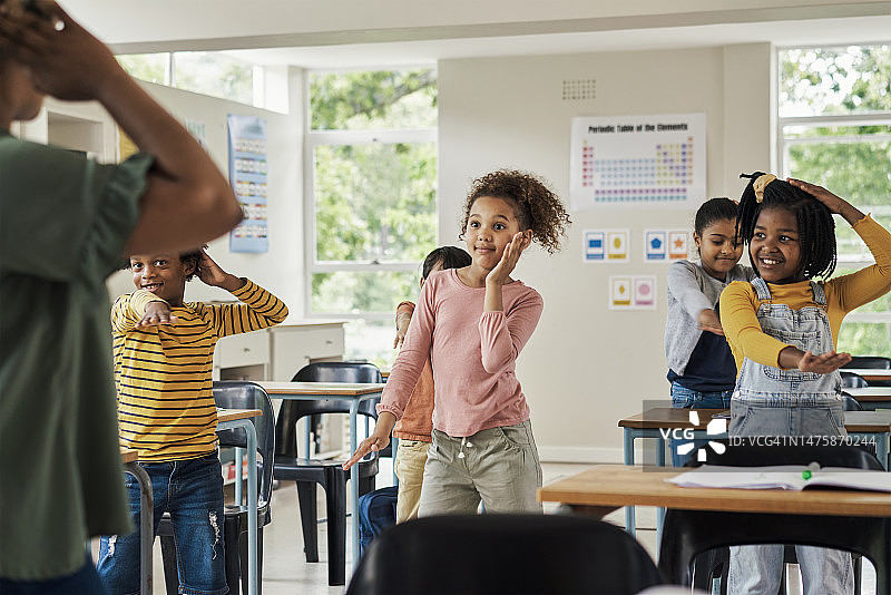 学校教室里，孩子们和老师一起跳舞，在学习、教育中快乐玩耍。多元化的孩子们和女老师一起教学、跳舞，享受寓教于乐的创意课程图片素材