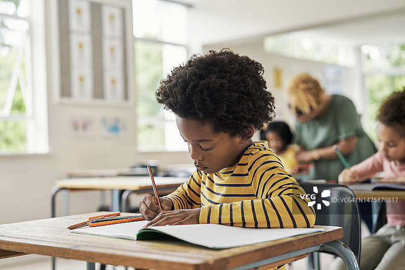 儿童在教室里学习写作，获取知识、信息和学术发展。在学校里，黑人男孩和学生们专心学习，认真备考图片素材