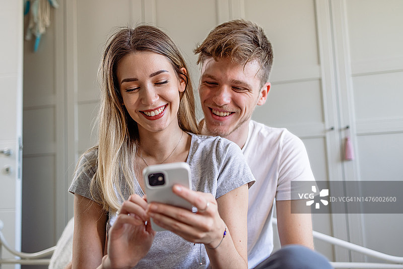 幸福夫妇在卧室使用智能手机的肖像图片素材