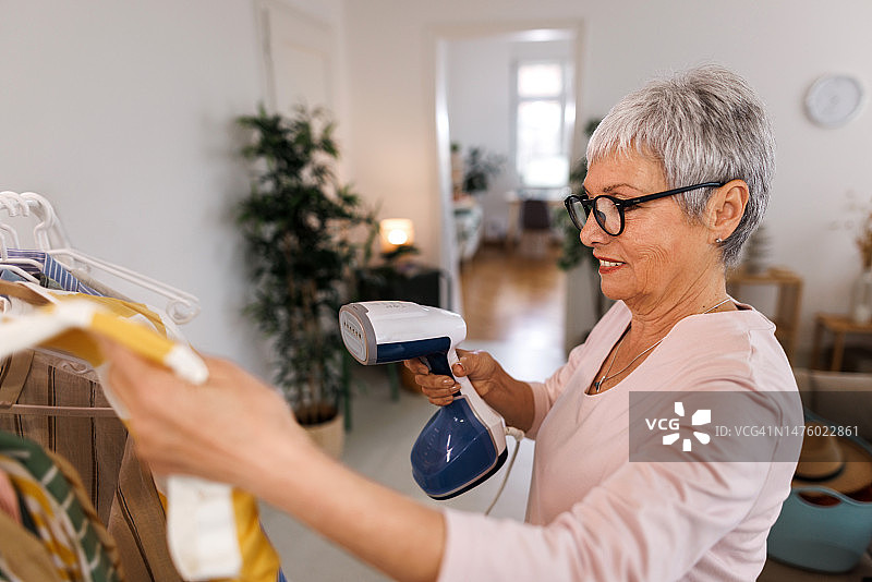 老年妇女在家中用晾衣架熨烫衣服图片素材