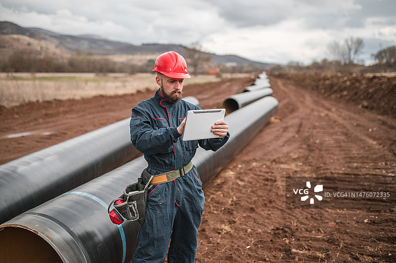 专注的工人在检查天然气管道的运行情况时使用数字平板电脑图片素材