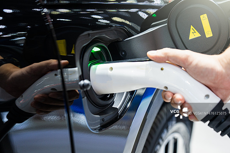 手将电缆插入电动汽车的特写图片素材