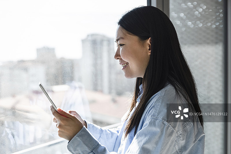 快乐的亚洲年轻女性使用平板电脑图片素材