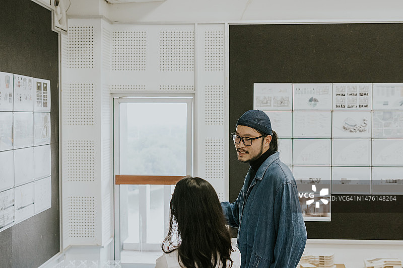 亚裔建筑师合伙人在礼堂谈论学生作品的设计方案图片素材