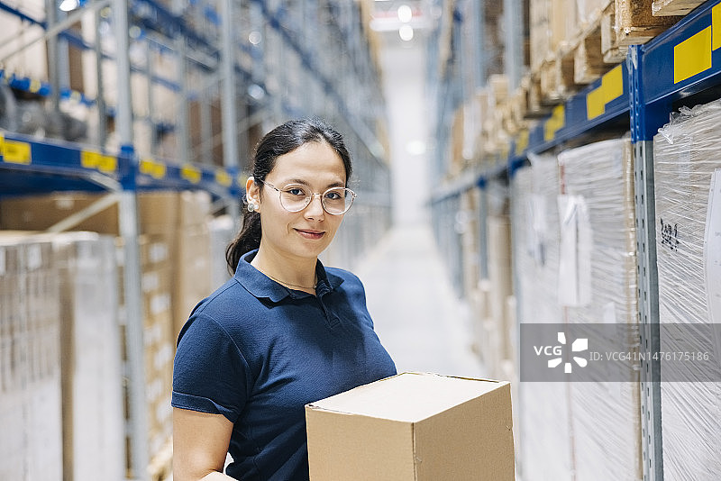 在仓库拿着纸箱的女员工肖像图片素材
