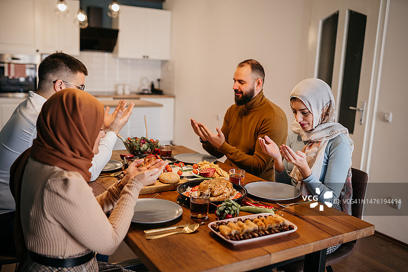 年轻家庭在斋月期间餐前祈祷图片素材
