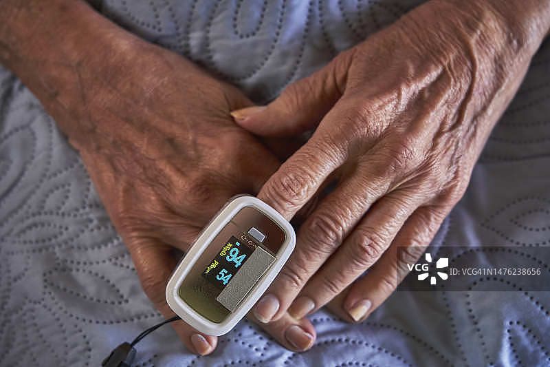 西班牙裔老年妇女展示测量血液中氧气水平的过程图片素材