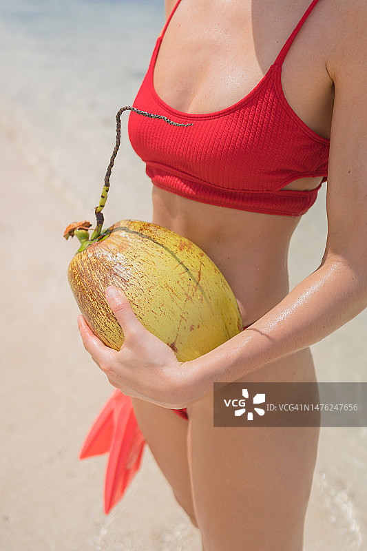 年轻女子在白色沙滩上拿着脚蹼和椰子图片素材