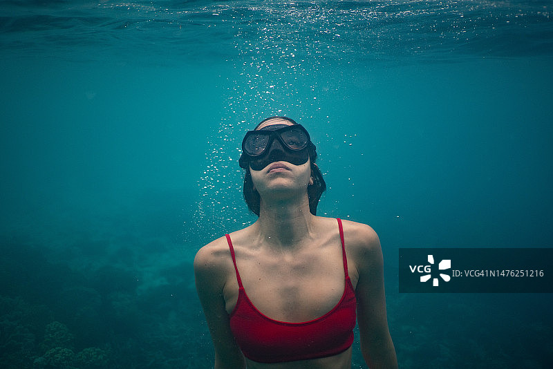 年轻女子戴着护目镜在水下游泳图片素材
