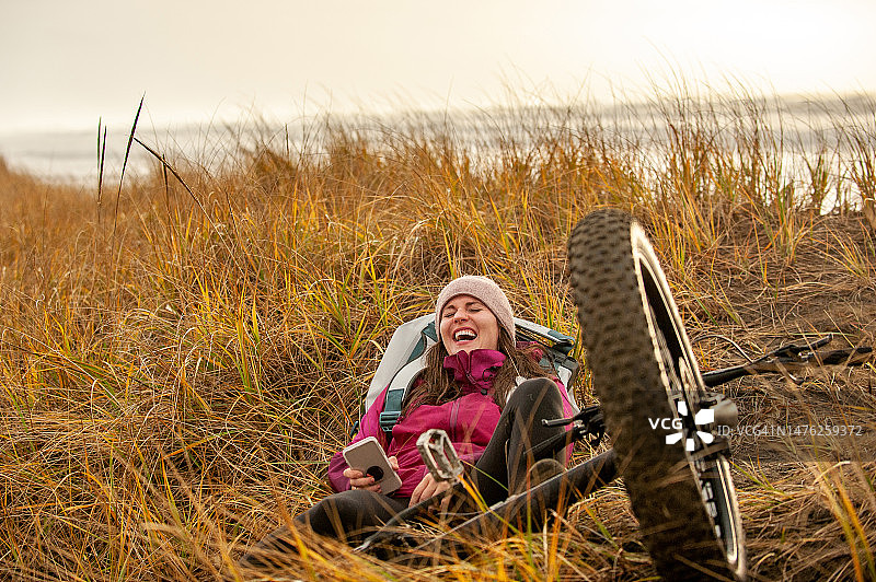 女人躺在草地上，身旁有自行车和手机图片素材