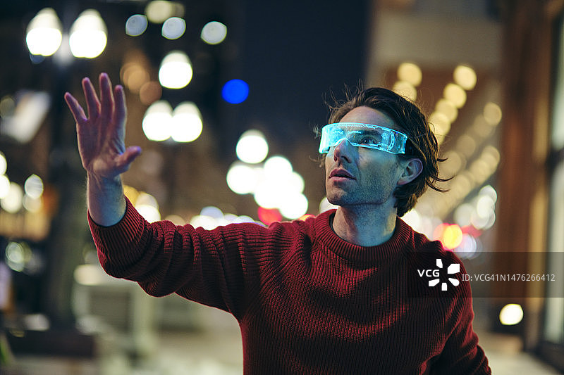 晚上在城市里戴虚拟眼镜的年轻人图片素材