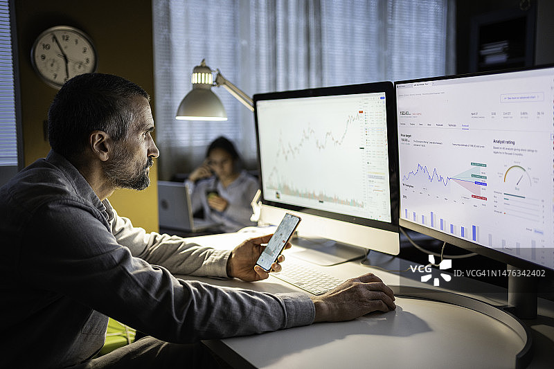 股票交易：交易员家庭在夜晚使用TradingView应用程序研究股票市场图片素材